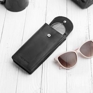 Flat lay view of double black leather glasses case on neutral background