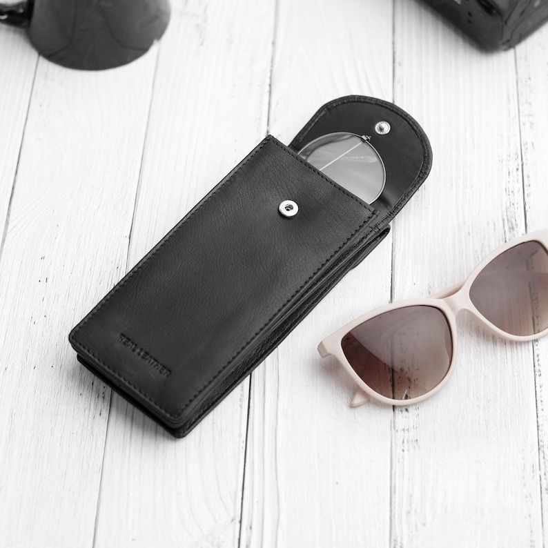 Flat lay view of double black leather glasses case on neutral background