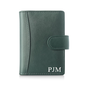 May include: A dark green leather wallet with a snap closure. The wallet has a vertical design with a curved seam on the left side. The initials "PJM" are printed in white on the lower right corner.