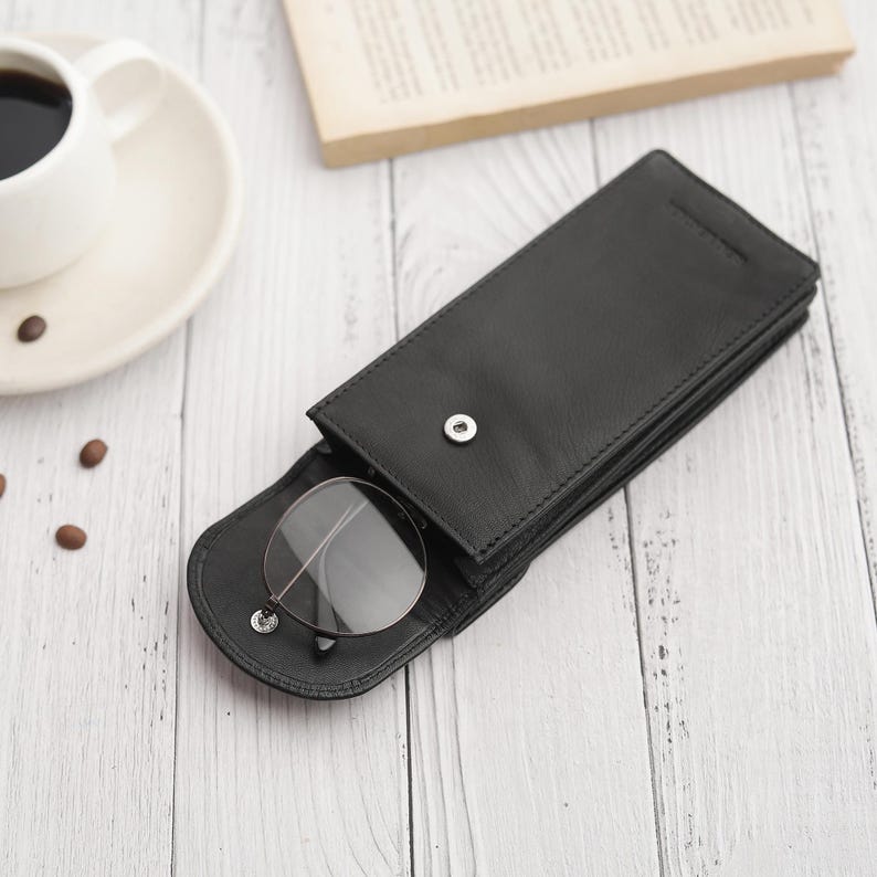 Flat lay view of double black leather glasses case on neutral background