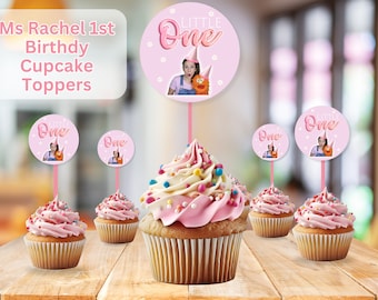 May include: Pink and white cupcake toppers with a photo of a girl and a puppet. The toppers say "Little One" in pink and white lettering.