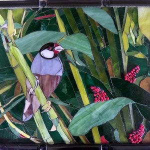 Può includere: Un'opera d'arte in mosaico che raffigura un piccolo uccello appollaiato su un gambo di bambù. L'uccello è grigio e marrone con un becco rosso. Lo sfondo è un verde lussureggiante con bacche rosse.