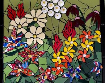 Op de afbeelding: Een kleurrijk mozaïekkunstwerk met verschillende bloemen in tinten rood, geel, wit en blauw. De bloemen zijn in een cluster gerangschikt, wat een levendig en opvallend ontwerp creëert.