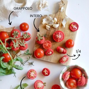 Può includere: Un assortimento di pomodori all'uncinetto, interi e tagliati, disposti su un tagliere di legno e in una ciotola. Aglio e foglie di basilico completano la composizione, suggerendo un tema culinario.
