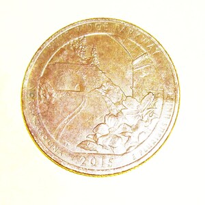 Puede incluir: Una moneda de un cuarto de dólar estadounidense de plata con la inscripción "Fort Bridge Parkway" y el año "2015".