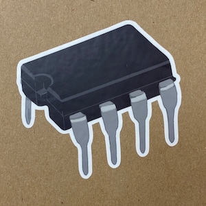Pode incluir: Um chip de circuito integrado preto com seis pinos. O chip é um componente comum em dispositivos eletrônicos.