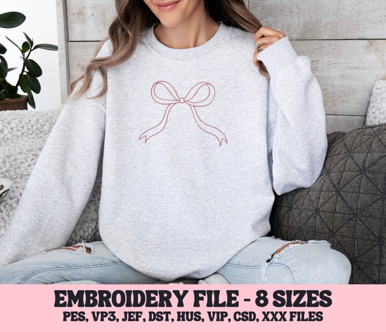 May include: A light gray sweatshirt featuring a minimalist bow design in a muted red-pink color. The text "EMBROIDERY FILE - 8 SIZES" is displayed in a pink banner at the bottom, along with file type abbreviations.