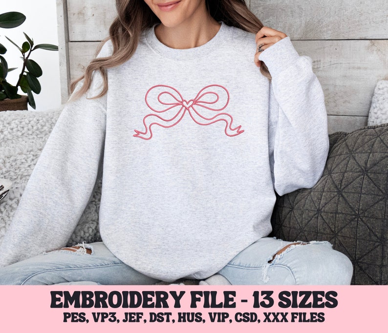 May include: A gray sweatshirt with a pink embroidered bow with a heart in the center. The sweatshirt is available in 13 sizes and in multiple embroidery file formats.