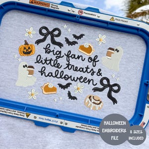 May include: A light gray t-shirt with an embroidered Halloween design. The design includes a jack-o'-lantern, ghosts, bats, pie slices, bows, and the text "big fan of little treats & halloween". The design is surrounded by a blue embroidery hoop.