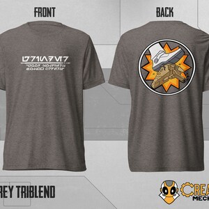 May include: A grey t-shirt with the text "L771A/V7" and a code underneath. The back of the shirt features a circular design with a white boot stepping on a small spaceship.