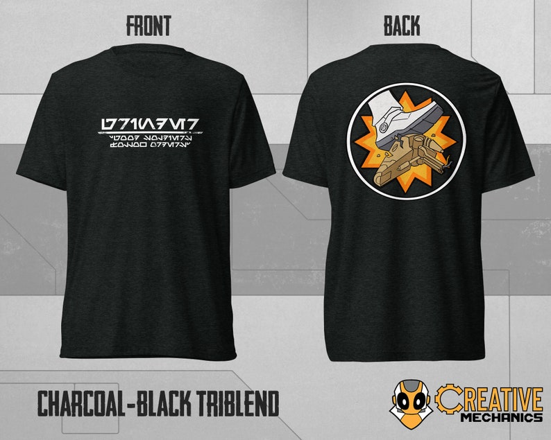 May include: A charcoal black triblend t-shirt with a white graphic on the front that says "L771A3M7" and "77007 707MT7". The back of the shirt features a white boot stomping on a brown spaceship with a yellow starburst behind it.