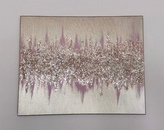 Pode incluir: Uma pintura em tela quadrada com um design abstrato de glitter rosa e prata. O glitter é em camadas em forma de onda.