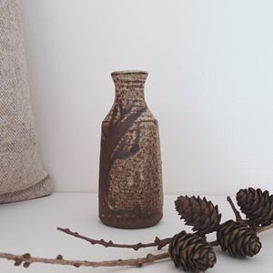 May include: A set of three ceramic mugs with a speckled, matte finish in cream, light grey, and dark grey. Each mug has a simple, minimalist design, suitable for coffee or tea.