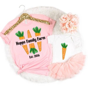 May include: Pink t-shirt with three cartoon carrots and the text "Hopps Family Farm Est. 2016". A white baby onesie with a single cartoon carrot.