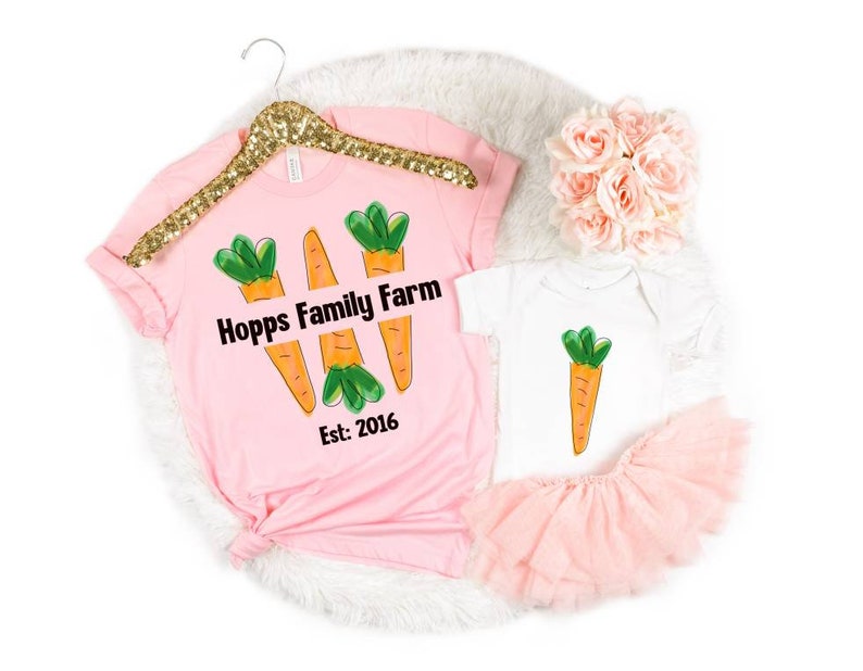 May include: Pink t-shirt with three cartoon carrots and the text "Hopps Family Farm Est. 2016". A white baby onesie with a single cartoon carrot.