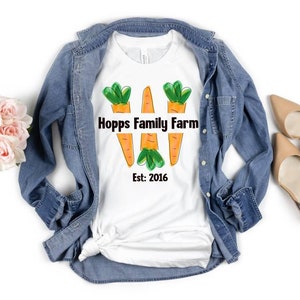 May include: White t-shirt featuring a design of three carrots and the text "Hopps Family Farm Est: 2016".