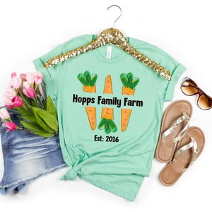 May include: A light green t-shirt with a graphic of three orange carrots and the text "Hopps Family Farm Est: 2016" printed on the front.