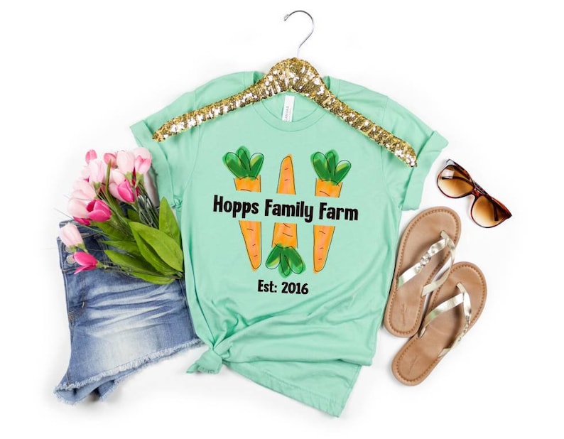 May include: A light green t-shirt with a graphic of three orange carrots and the text "Hopps Family Farm Est: 2016" printed on the front.