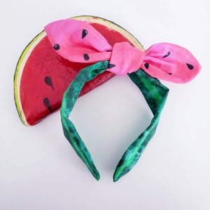 Puede incluir: Diadema de sandía con una banda de patrón verde y blanco y un lazo de sandía rosa.