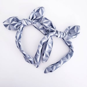 May include: Two gray and white geometric patterned headbands with a bow knot.