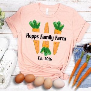 May include: A pink t-shirt with a graphic of three carrots and the text "Hopps Family Farm Est: 2016".
