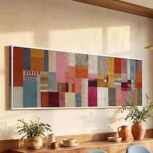 Könnte beinhalten: Ein langes, rechteckiges Wandkunstwerk mit einem Raster aus vertikalen und horizontalen Blöcken in Orange-, Rosa-, Blau-, Rot- und Cremetönen. Das Kunstwerk hängt über einem hölzernen Sideboard und einem Esstisch mit blauen Stühlen.