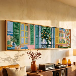 May include: A long, rectangular framed painting depicting a Mediterranean scene with open windows, green shutters, an orange tree, and a floral curtain. The artwork features vibrant colors including yellow, green, blue, and orange, displayed on a wall.