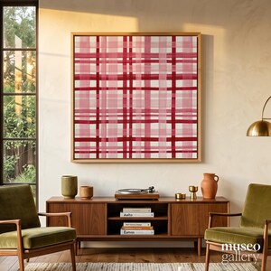 Puede incluir: Una pieza de arte mural cuadrada con un patrón de cuadros rosa y rojo oscuro, enmarcada en madera clara. La obra se exhibe sobre un mueble multimedia de madera con libros y objetos decorativos, con el texto museo gallery en la esquina.