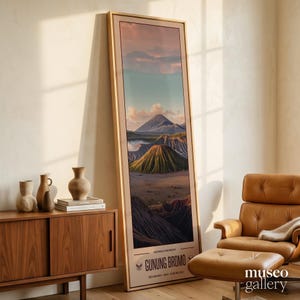 Könnte beinhalten: Ein gerahmter vertikaler Landschaftsdruck mit einer Bergkette und einem Vulkan. Das Kunstwerk hat einen beigen Rahmen und den Text "GUNUNG BROMO" unten. Die Farbpalette umfasst Grün-, Braun- und Blautöne.