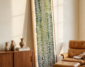 May include: A tall, rectangular framed wall art piece featuring three vertical columns of stylized green fern leaves on a cream background. The artwork is encased in a light-colored wooden frame and leans against a wall, showcasing a botanical print.