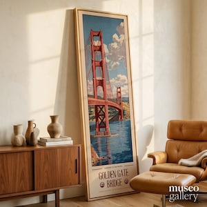 May include: A tall, rectangular framed print featuring a vintage-style illustration of the Golden Gate Bridge in red, spanning blue water under a cloudy sky. The text at the bottom reads Gateway to the Pacific Golden Gate Bridge with a small logo.