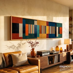 May include: A long rectangular wall art piece in a wooden frame featuring a geometric composition of vertical stripes and solid blocks in shades of deep blue, burnt orange, mustard yellow, black, and cream, displayed above a wooden media console.
