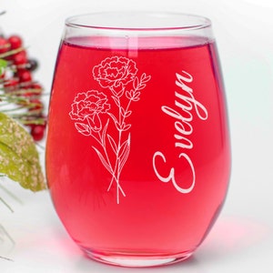 Op de afbeelding: Een helder glazen wijnglas met een rode vloeistof erin. Het glas heeft een wit bloemenmotief en de naam "Evelyn" is gegraveerd op de zijkant.