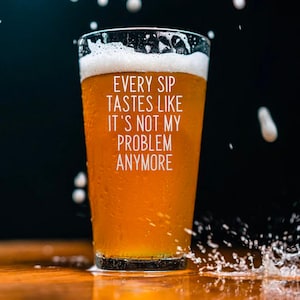 Pode incluir: Um copo de cerveja &acirc;mbar com uma espuma branca. O copo tem condensa&ccedil;&atilde;o e o texto branco "EVERY SIP TASTES LIKE IT'S NOT MY PROBLEM ANYMORE". Gotas e salpicos de &aacute;gua rodeiam o copo.