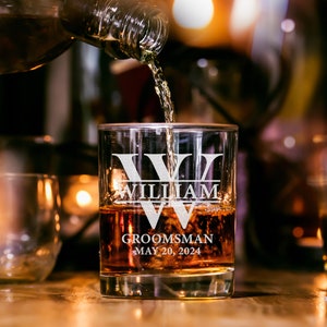 May include: A personalized glass with the text "William" and "Groomsman May 20, 2024" etched on it. Whiskey is being poured into the glass.