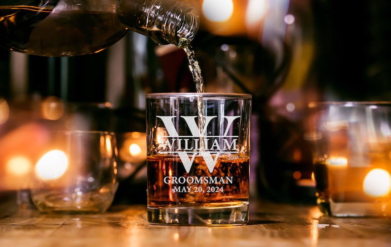 May include: A personalized glass with the text "William" and "Groomsman May 20, 2024" etched on it. Whiskey is being poured into the glass.