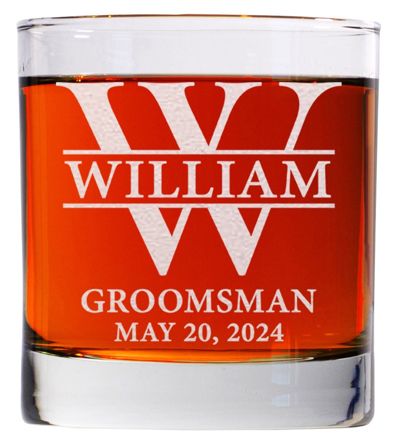 May include: A clear glass whiskey tumbler with a white etched design. The design features a large letter "W" with the name "William" above it and the words "Groomsman May 20, 2024" below it.