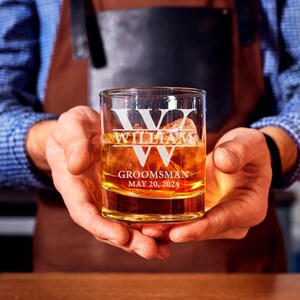 May include: A clear glass whiskey tumbler with the name "William" etched on the front. The glass also has the words "Groomsman" and "May 20, 2024" etched on it.