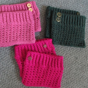 May include: Four crocheted leg warmers with button closures. Two are pink and two are dark green.