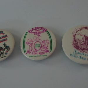 Puede incluir: Tres insignias vintage de "Easter at the White House". Las insignias son blancas con gráficos y texto coloridos. Una presenta a Mickey Mouse, otra tiene un diseño con el texto "Happy Easter", y la tercera muestra un edificio.