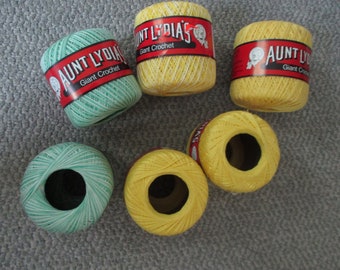 May include: Six balls of yarn in green and yellow with the text "Aunt Lydia's Giant Crochet" on the labels.