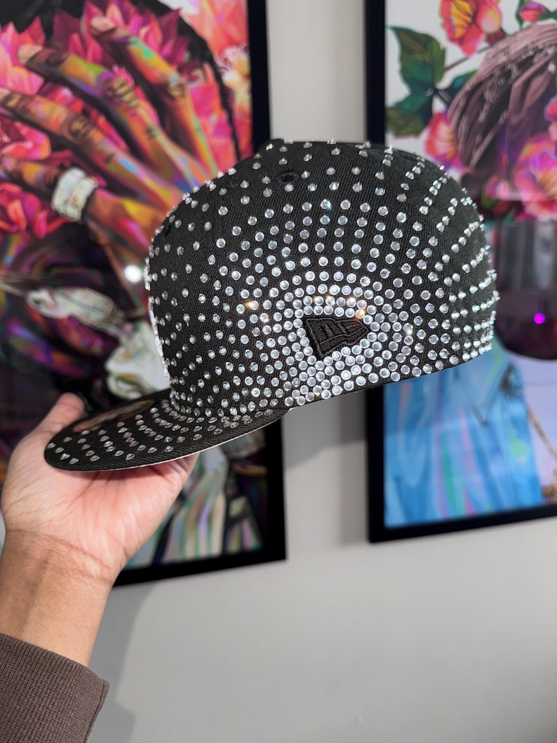 Pode incluir: Um bon&eacute; de beisebol preto com um grande padr&atilde;o de diamantes de imita&ccedil;&atilde;o brancos em forma de diamante. O bon&eacute; tem uma viseira preta e um logotipo New Era preto na frente.