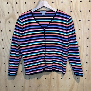 May include: A colourful striped cardigan with a V-neck and button fastening. The sweater has horizontal stripes in black, pink, orange, blue, and yellow. The brand name "Designers" is visible on the label.