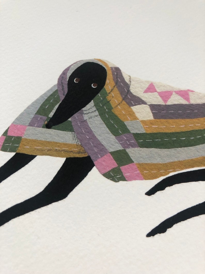 K&ouml;nnte beinhalten: Ein schwarzer Hund mit gro&szlig;en Augen ist in eine bunte Patchwork-Decke gewickelt. Die Decke hat rosa, gr&uuml;ne, gelbe und graue Quadrate mit wei&szlig;en N&auml;hten.