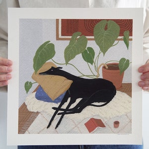 May include: A black and white illustration of a dog lying on a white rug with a green plant in a terracotta pot in the background. The dog is resting its head on a yellow pillow. There is a red book and a small cup on the rug.