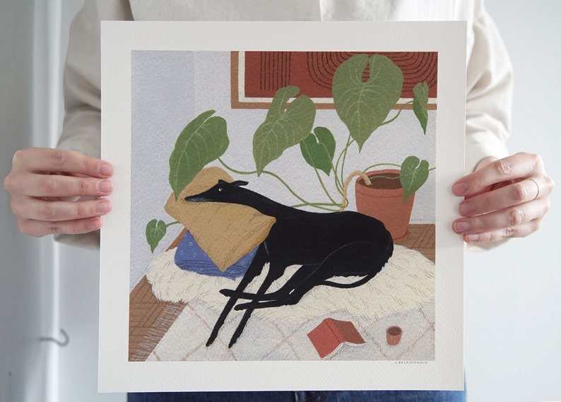 May include: A black and white illustration of a dog lying on a white rug with a green plant in a terracotta pot in the background. The dog is resting its head on a yellow pillow. There is a red book and a small cup on the rug.