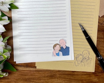 May include: Two sets of lined stationery with illustrations of a couple and a family. The stationery is on a wooden surface with a bouquet of white flowers.