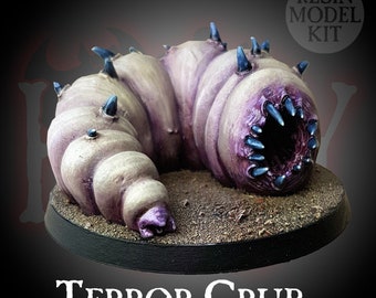 May include: A resin model kit of a purple and white grub with blue spikes and a large mouth. The grub is sitting on a brown base with the text "Terror Grub" and "Resin Model Kit" on the base.