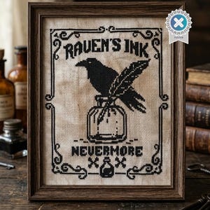 Può includere: Un ricamo a punto croce incorniciato raffigurante un corvo nero appollaiato su un calamaio con una penna. Il testo recita "RAVEN'S INK" in alto e "NEVERMORE" in basso, con una piccola icona di calamaio affiancata da due simboli X sotto il testo.