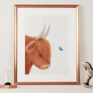 May include: A framed illustration of a Highland cow with a fluffy brown coat and large horns, looking to the right at a small blue butterfly.